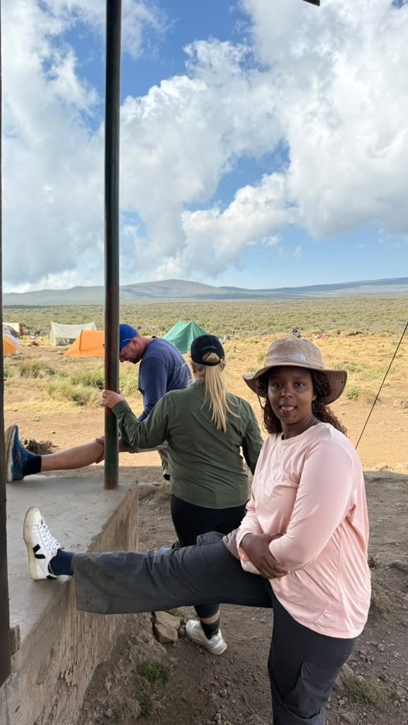 A climber sitting beside a tent at a rocky mountain camp