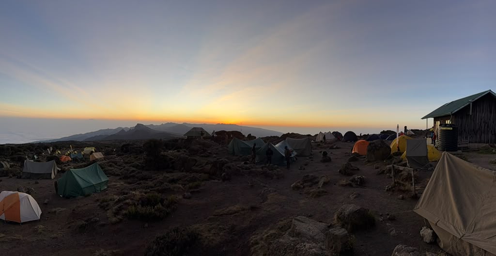 Mountain tents silhouetted beneath a warm evening sky