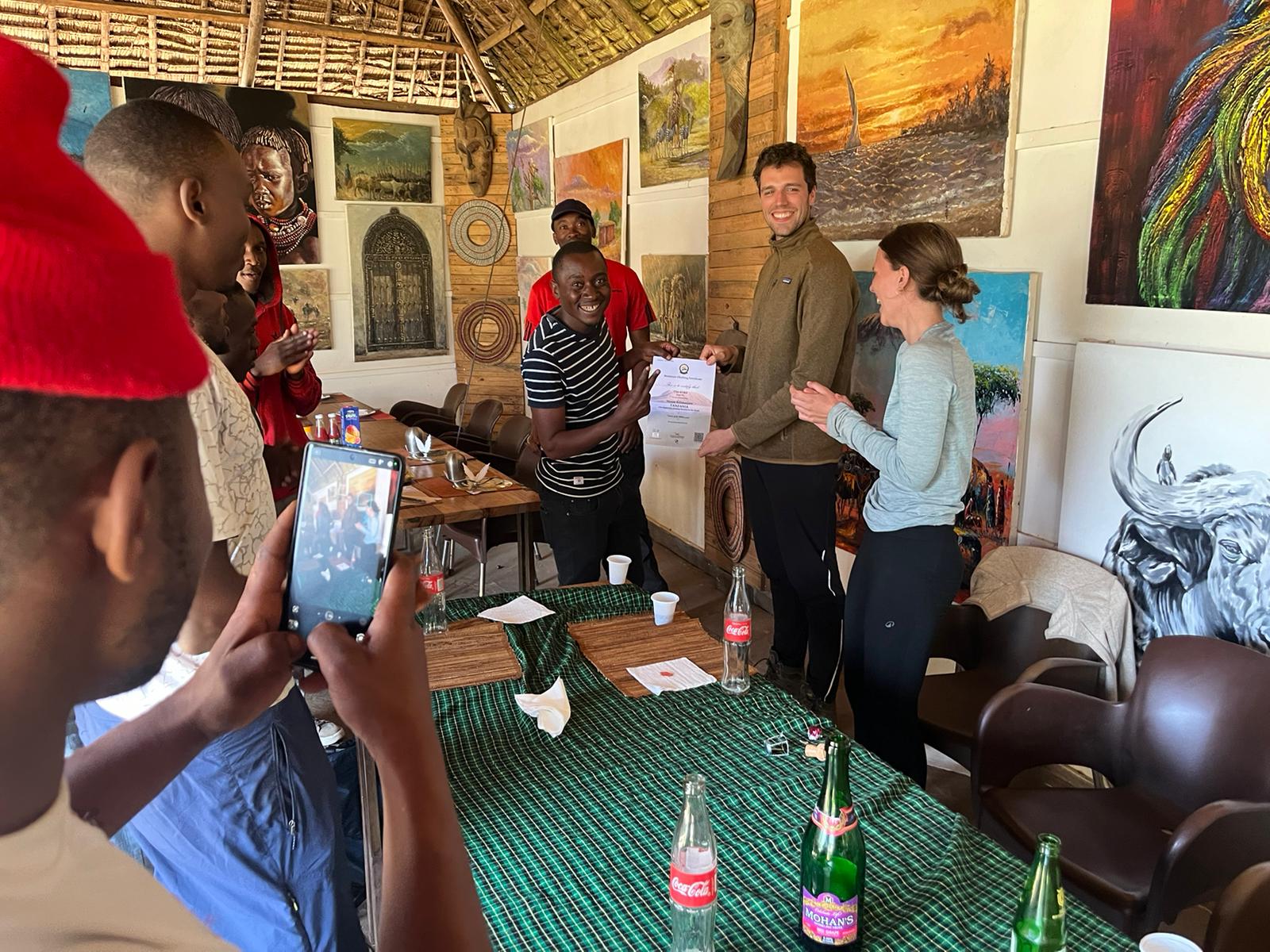 Climbers and crew gathered indoors for a certificate presentation
