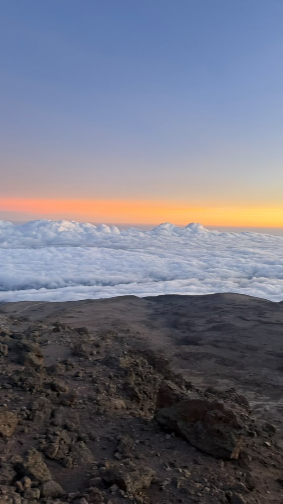 Orange dawn light stretching across a deep layer of clouds