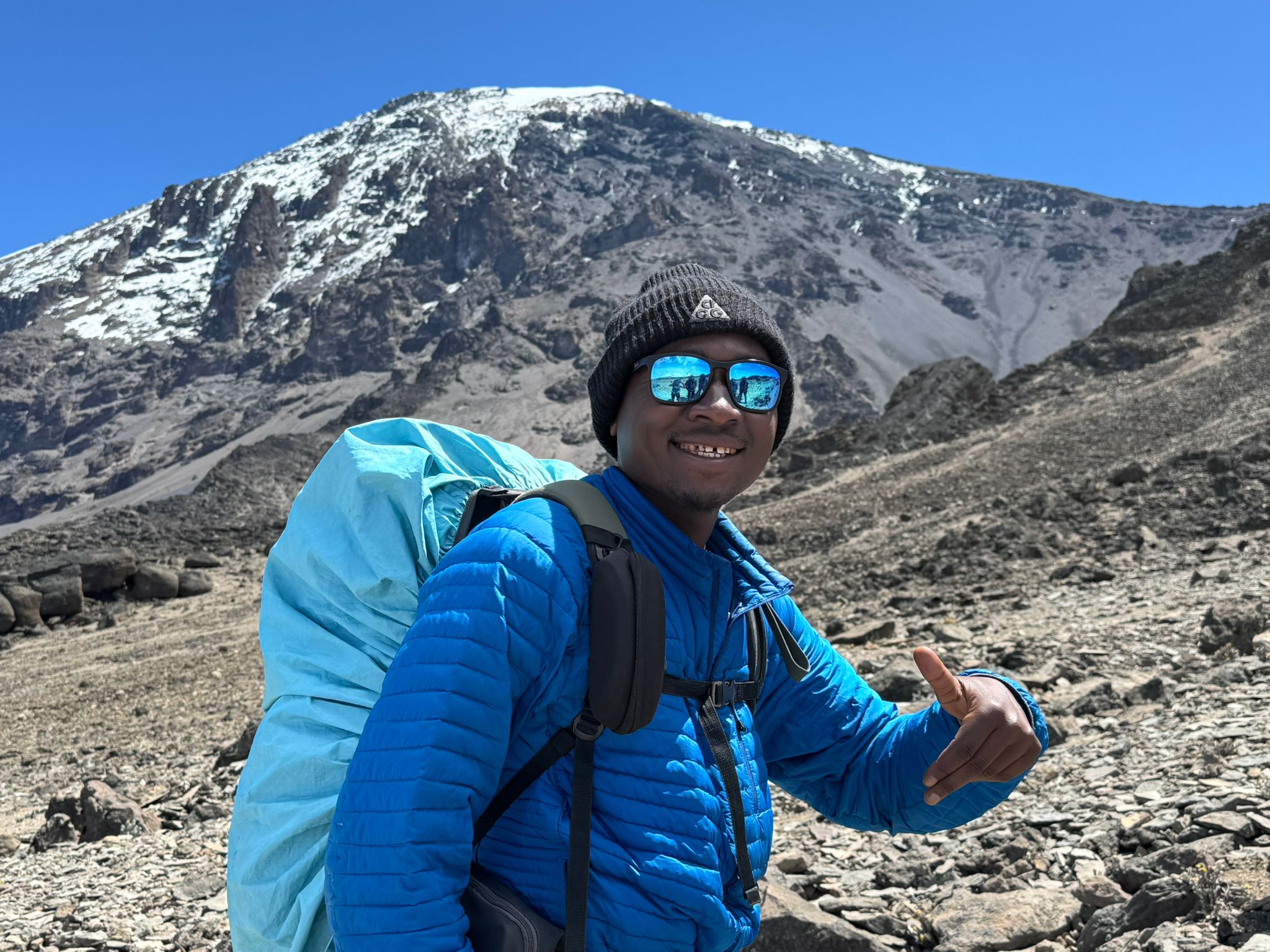 A local mountain guide standing with open arms before a snowy peak