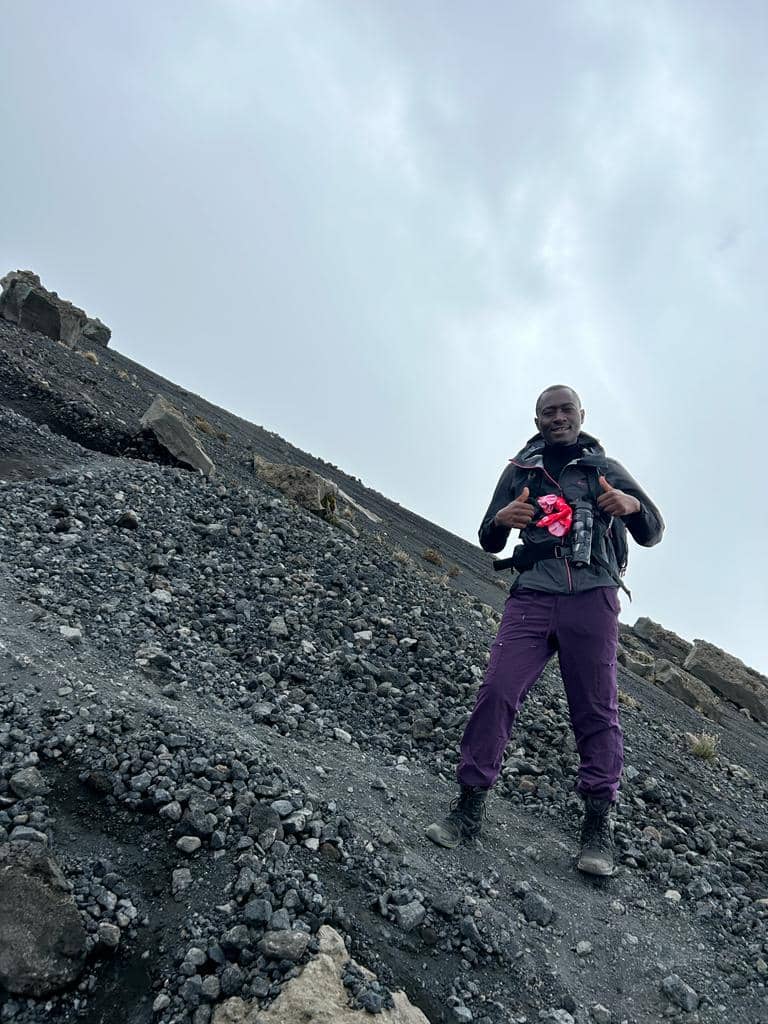 A lone mountain guide walking across a steep dark scree slope