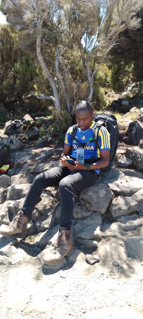 A mountain guide sitting to rest among large dark rocks