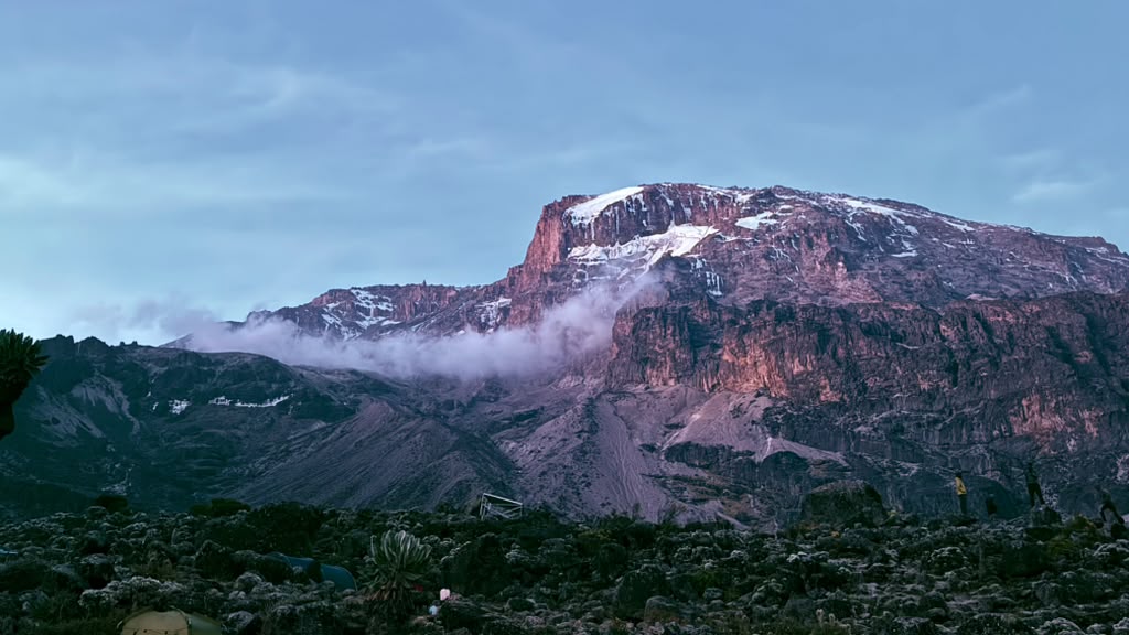 A broad mountain face illuminated by soft pink light