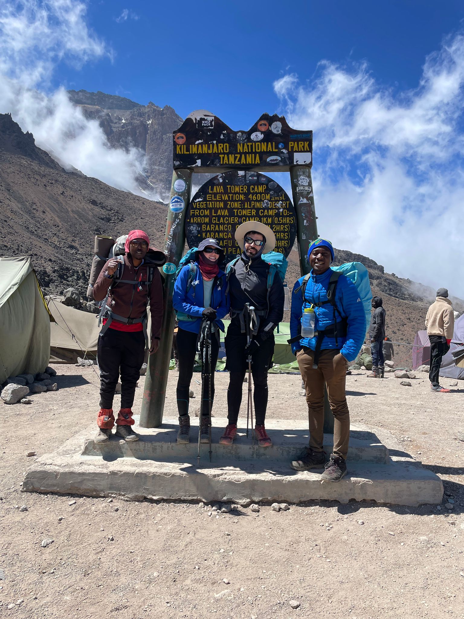 Four climbers posing beside a wooden sign in misty weather