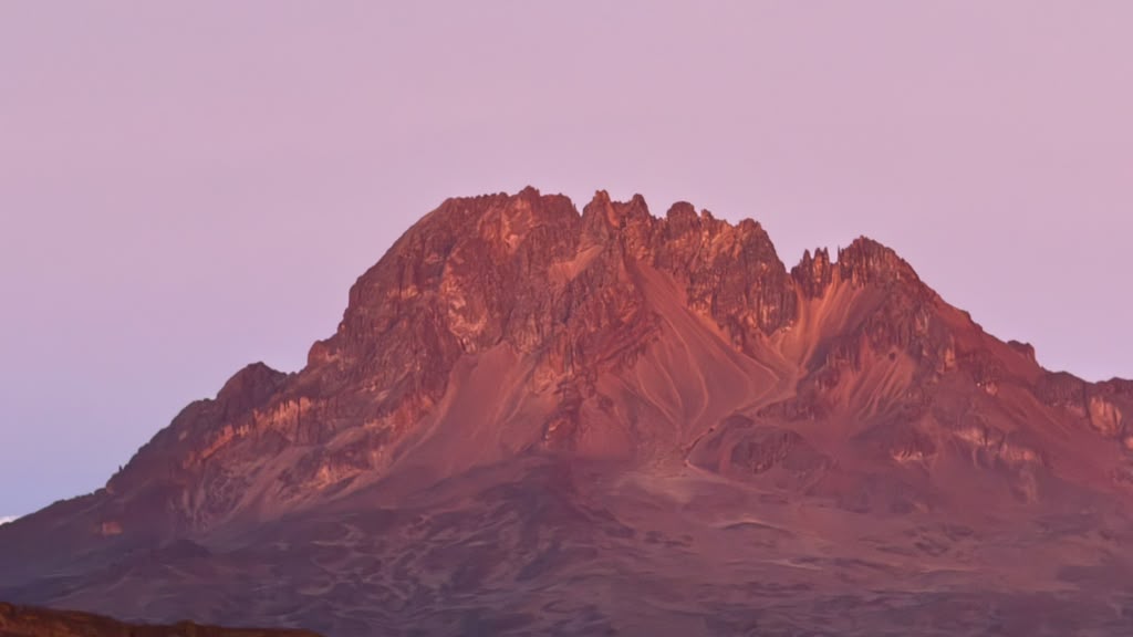 Jagged mountain ridges glowing pink in early light