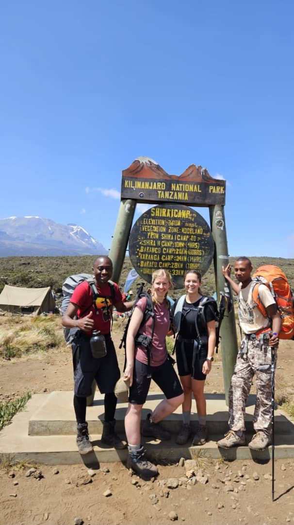 Four hikers standing together beside a colourful wooden trail sign