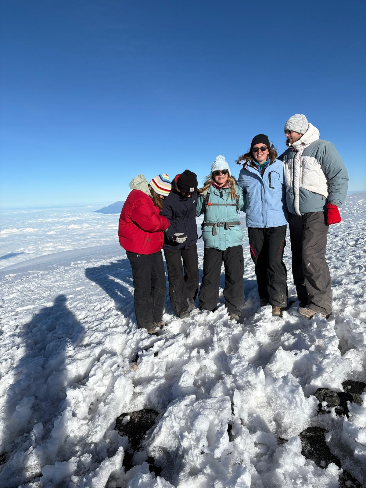 Five climbers standing together on a bright snow-covered slope