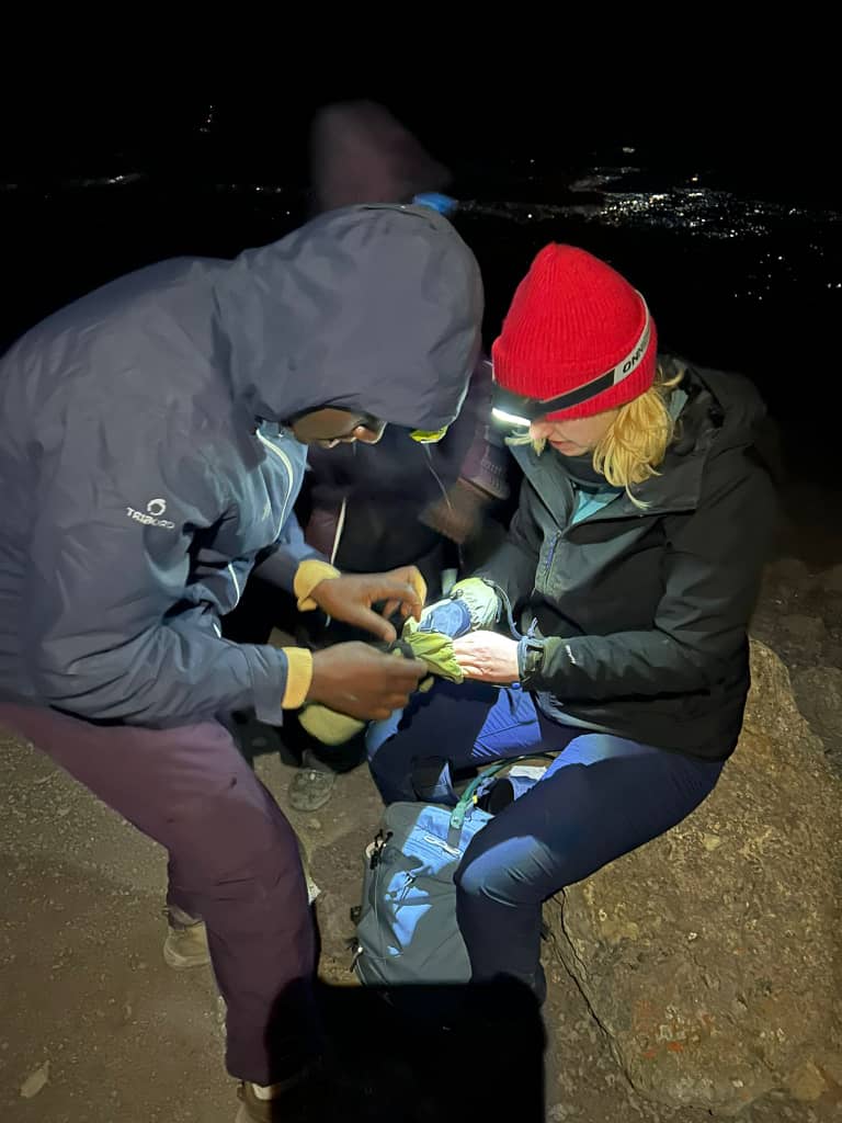 Two climbers adjusting warm clothing by torchlight at night