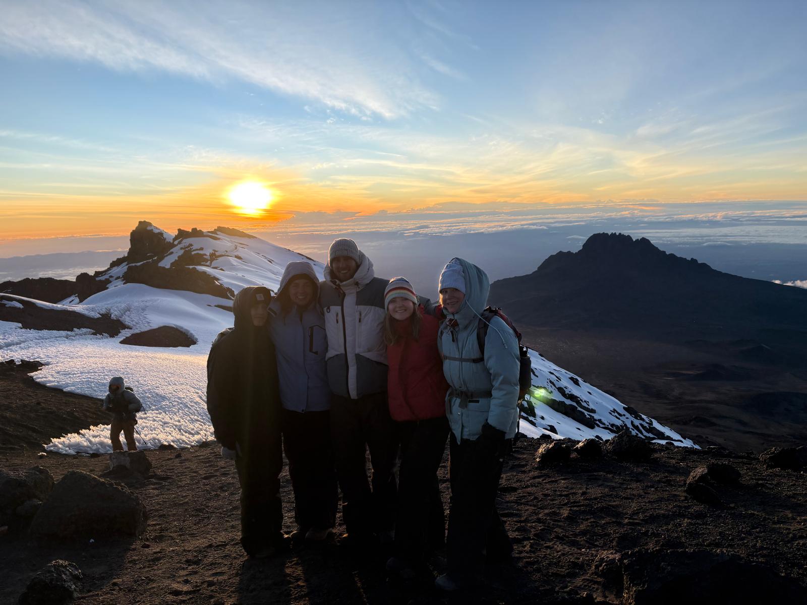 A group of climbers standing together as the sun rises over snowy slopes