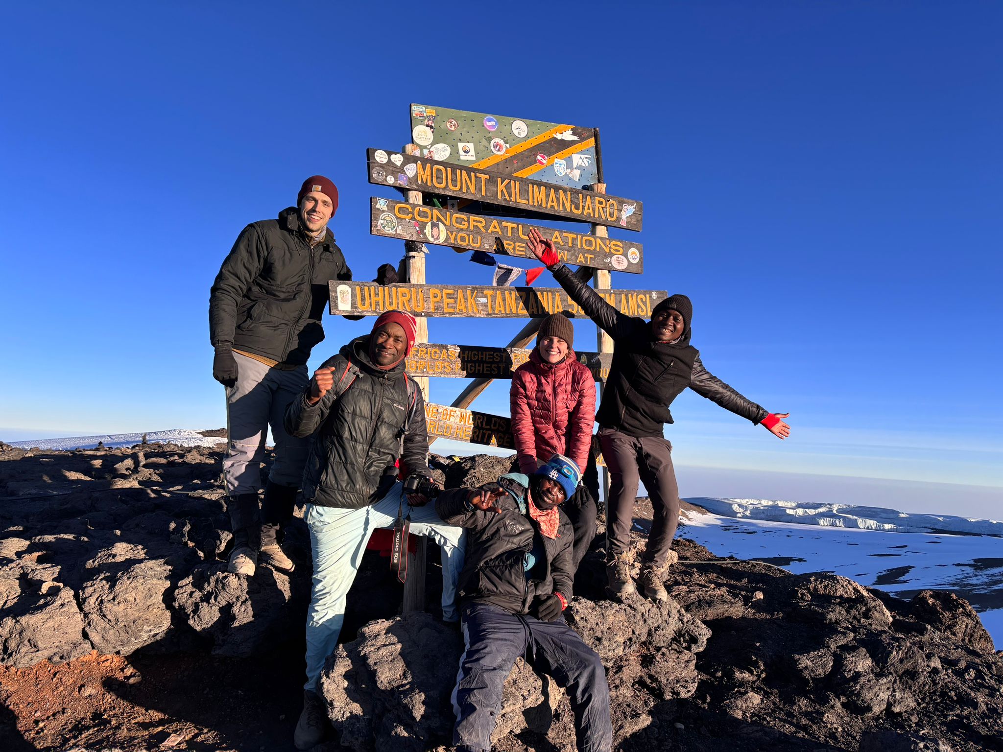 A group of climbers celebrating beside a summit sign