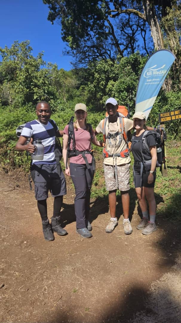 Five hikers standing together at the start of a forest trail
