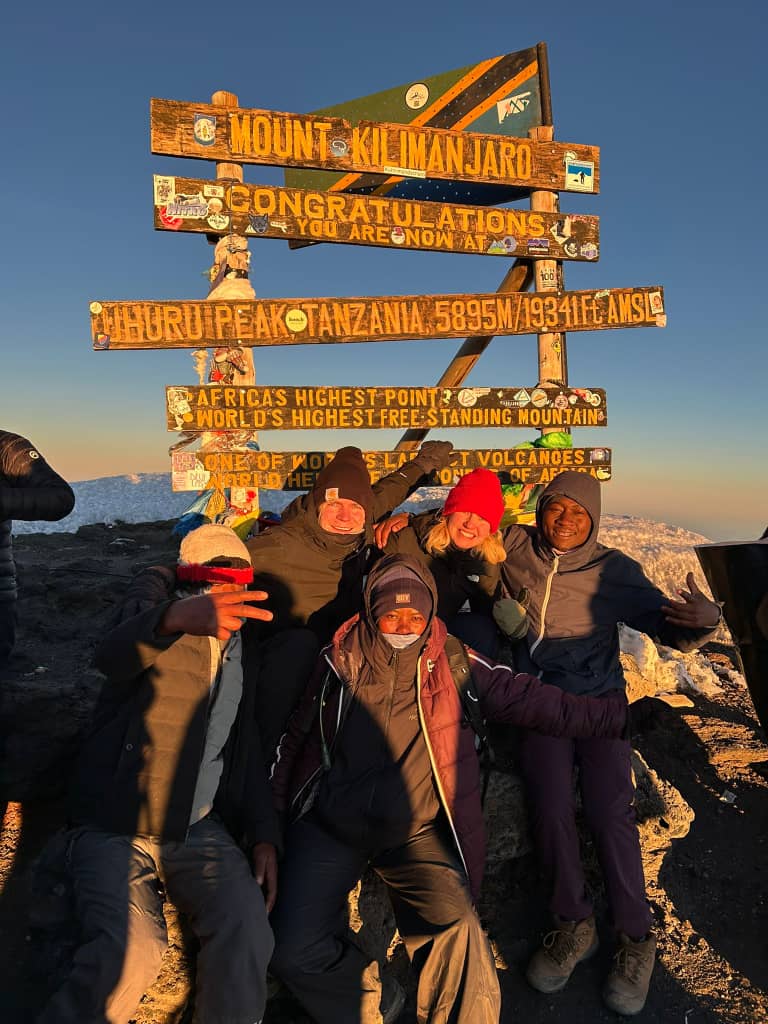 A group celebrating together around wooden summit signs